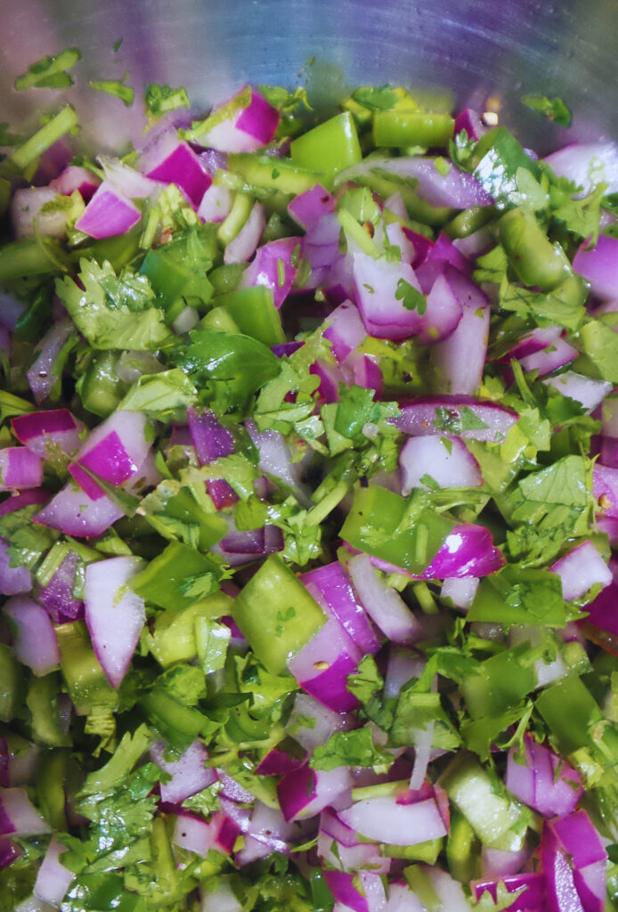 diced onion, peppers and cilantro in a stainless steel bowl