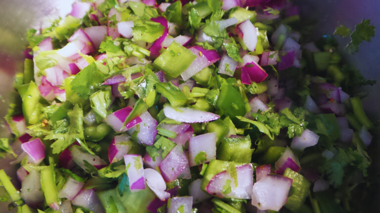 chopped onions, peppers and cilantro in a stainless steel bowl