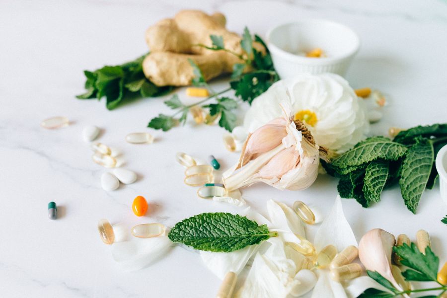 herbalism supplements and mint leaves, ginger and garlic scattered on a table top