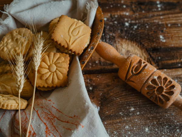 wheat heads, flower shaped cookies and a decorated rolling pin on a wooden table