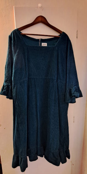 green corduroy dress on a wooden hanger