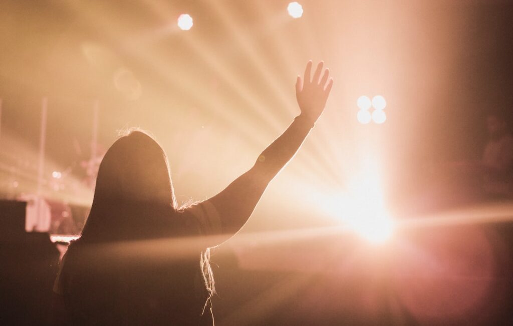 a silhouette of a woman raising her hand in a spotlight 